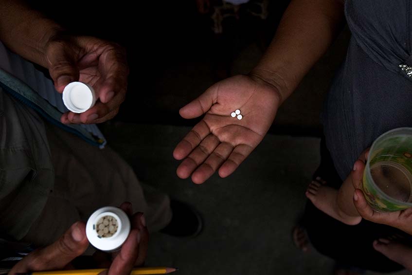 A hand holding three Mectizan tablets.