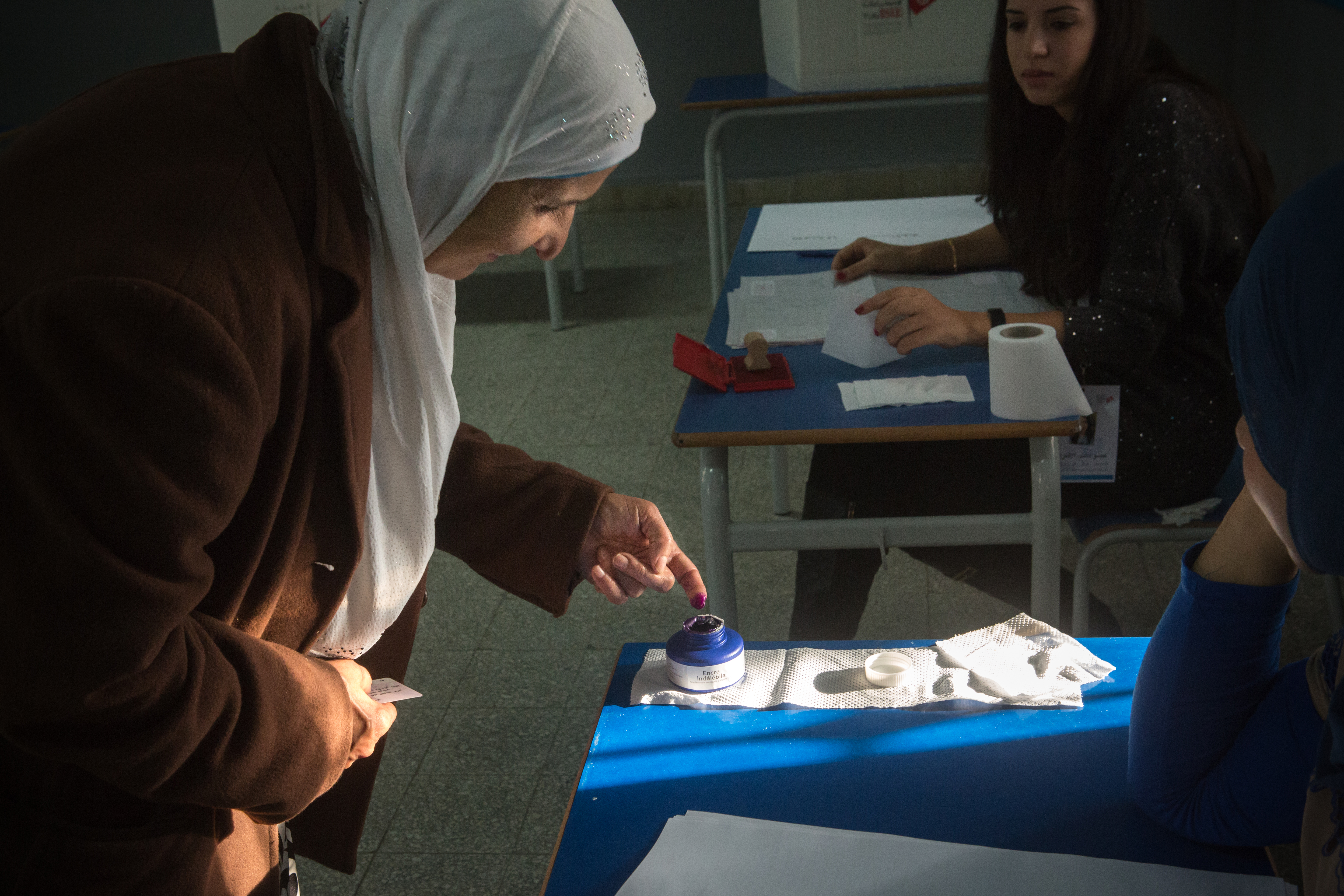 A voter dips her finger in the ink till just before she fills out her ballot. The visual identification that she has voted will wear off after a few weeks of daily handwashing. 