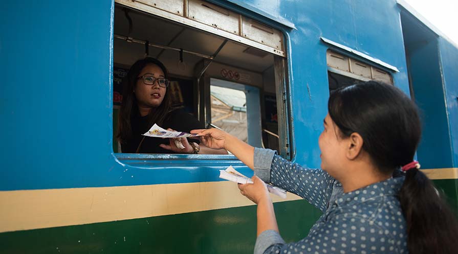 Photo of a woman distributing voting information to a passenger on a commuter train.