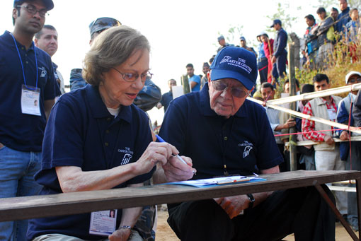 Photo of President and Mrs. Carter completing a polling center opening form while waiting for voting to begin in Bhaktapur, Nepal.