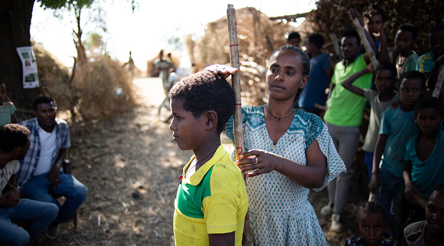 a woman measure a young man's height to determine his dose of medication.