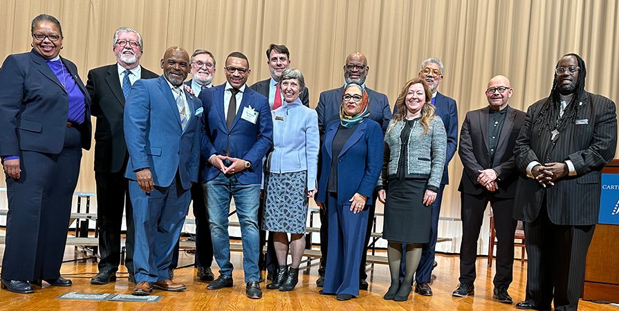 PEople stand shoulder to shoulder on a stage.